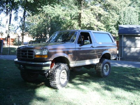 1993 Ford Bronco - Brown 1993 Ford Bronco with a lift kit and large tires sits in a yard.
