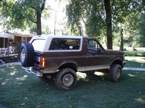 1993 Ford Bronco - This lifted Ford Bronco is covered in mud, suggesting recent off-road use.
