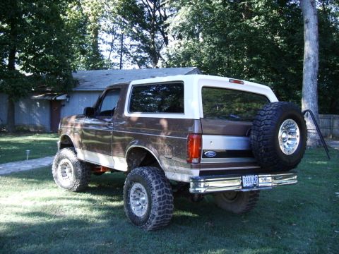 1993 Ford Bronco - This lifted 1993 Ford Bronco is shown from the rear, a brown and white paint scheme and a spare tire mounted on the back.