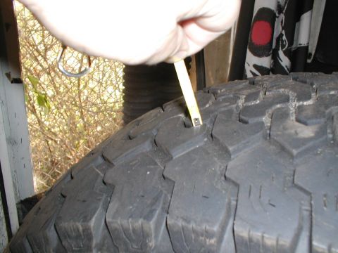 1979 Ford Bronco - Measuring tire tread depth with a tape measure.