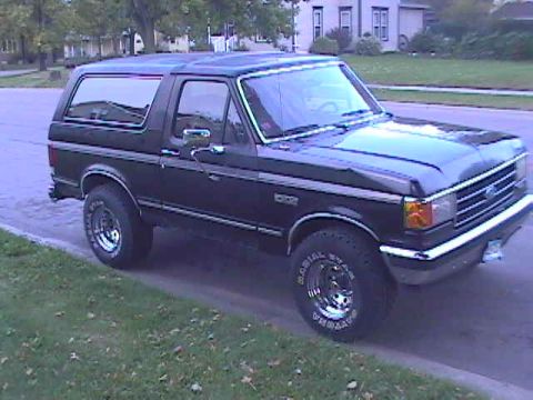 1989 Ford Bronco - This black Ford Bronco is parked on the side of a residential street, viewed from a three-quarter front angle.