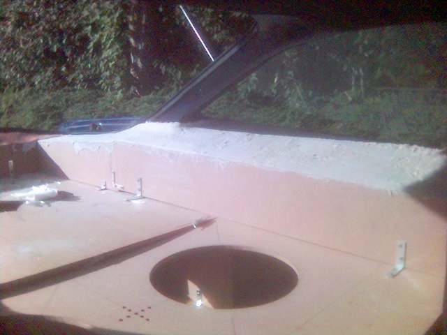 Car trunk area with pink insulation and a circular cutout, unfinished bodywork visible. Supermotors.net watermark