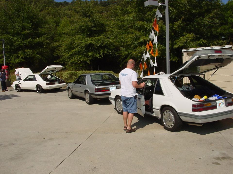 White Ford Mustang with trunk open, parked next to a silver Mustang