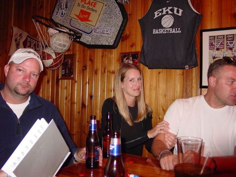 1986 Ford Mustang - People gather at a bar, with sports memorabilia adorning the wood-paneled walls.