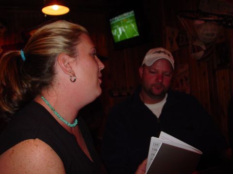 1986 Ford Mustang - A woman and a man are seated at a table, with a television in the background showing a football game.