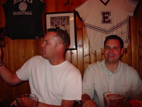 1986 Ford Mustang - Two men are seated at a table, with sports memorabilia visible on the wall behind them.
