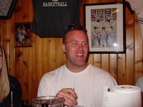 1986 Ford Mustang - A man smiles while sitting at a table, with sports memorabilia visible on the wall behind him.