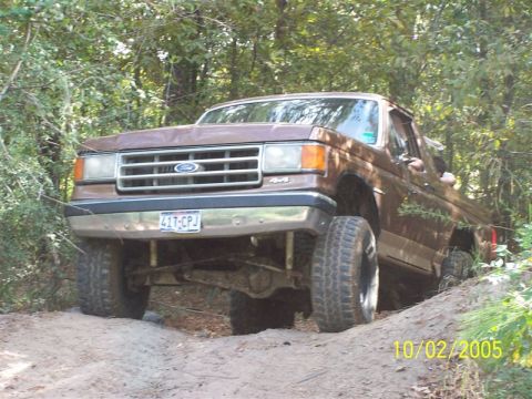 1987 Ford Bronco - A brown 1987 Ford Bronco navigates an off-road trail.