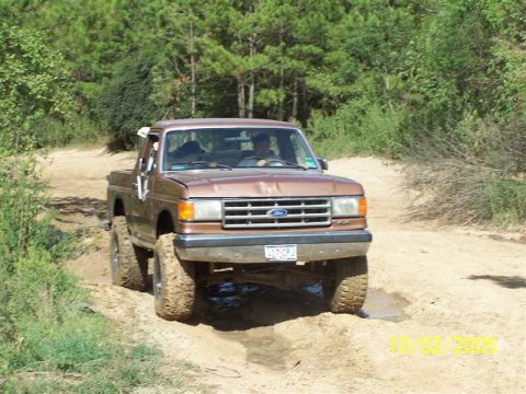 1987 Ford Bronco - This 1987 Ford Bronco navigates an off-road trail, its large tires kicking up dirt and water.