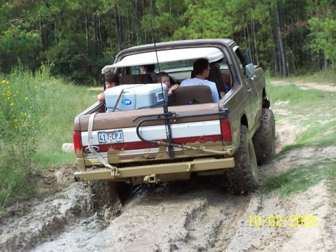 1987 Ford Bronco - 1987 Ford Bronco navigating a muddy trail with passengers and fishing gear.