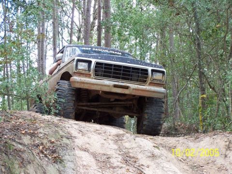 1987 Ford Bronco - Off-road vehicle with large tires climbing a dirt hill. Text on hood reads "JEEP RESCUE TEAM".