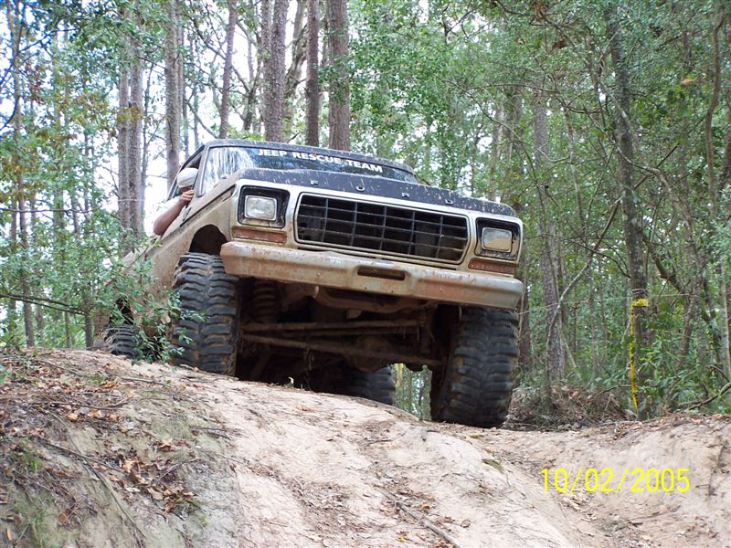 Off-road vehicle with large tires climbing a dirt hill, "JEEP RESCUE TEAM" text on hood