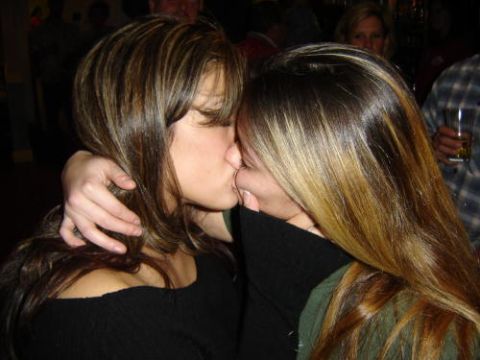 2004 Ford F-150 - Two women share a kiss while others are visible in the background of a social gathering.