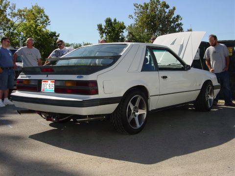 1986 Ford Mustang - A white 1987 Ford Mustang hatchback is displayed with its hood open at an outdoor car event.