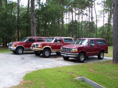 1989 Ford Bronco - Three Ford SUVs parked in a driveway, including a 1992-1996 Bronco and a Ford Excursion.