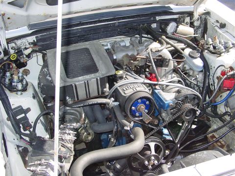 1986 Ford Mustang - The engine bay of a 1986 Ford Mustang, a turbocharger and various aftermarket components.
