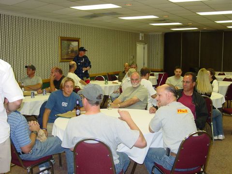 1986 Ford Mustang - A group of people are seated at tables in a room, possibly at a gathering or event.