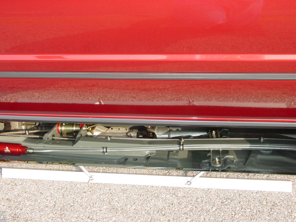 red car side panel with visible undercarriage components and a "SUPERMOTORS.NET" watermark