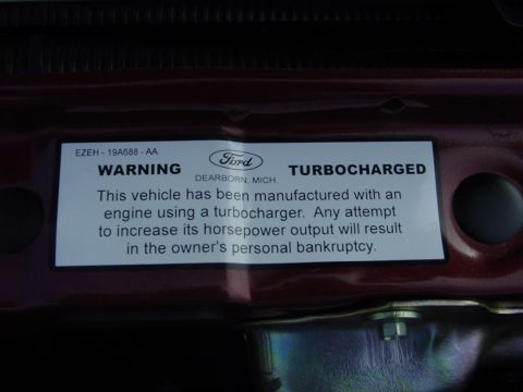 1986 Ford Mustang - Warning sticker on a vehicle's engine indicating it is turbocharged and manufactured in Dearborn, MI.
