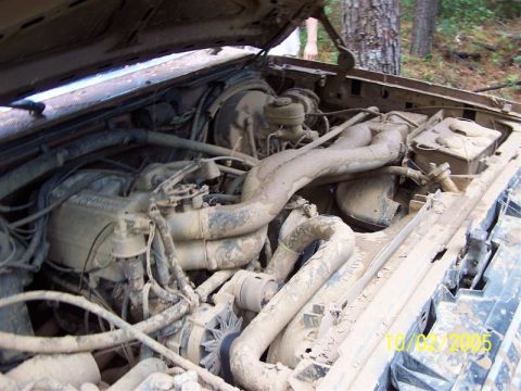 1987 Ford Bronco - The engine bay of a vehicle is heavily covered in mud, with a date stamp visible in the lower right corner.