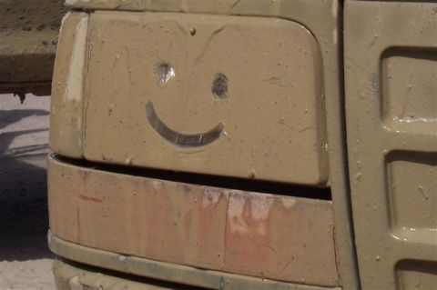 1987 Ford Bronco - A smiley face is drawn in the mud on a vehicle's headlight, giving it a cheerful appearance.