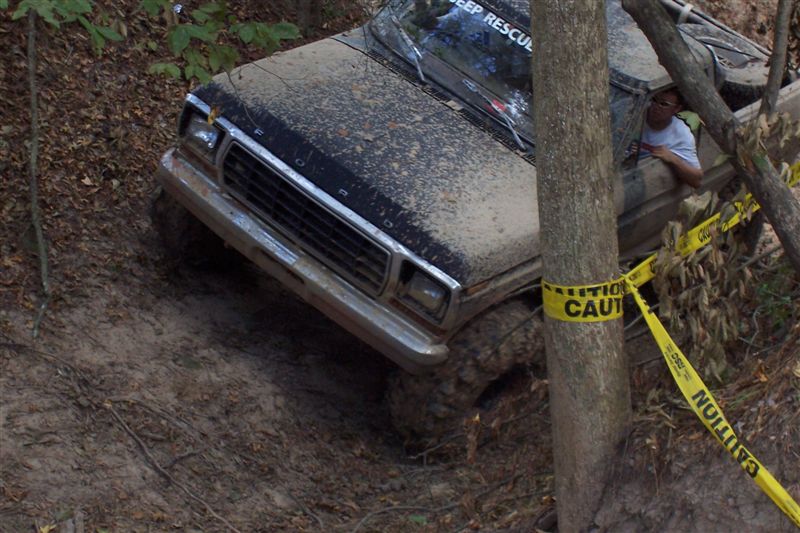 Muddy truck stuck on a hill, caution tape around a tree