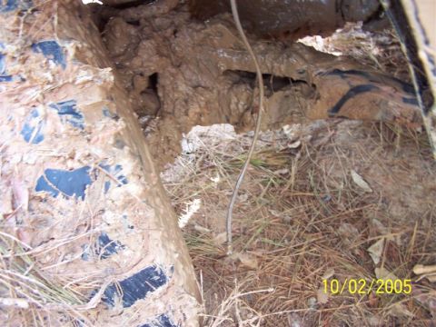 1987 Ford Bronco - A close-up view of a heavily mud-covered vehicle tire and undercarriage, with visible date stamp 10/02/2005.