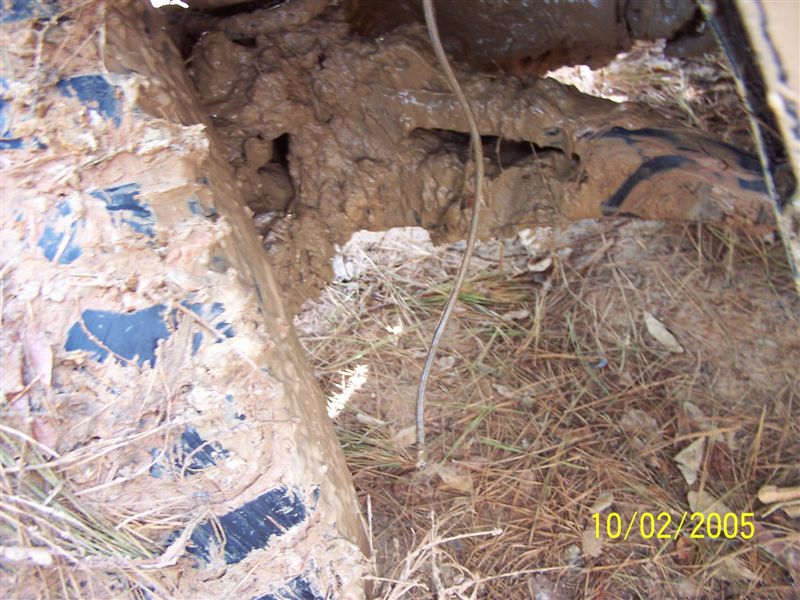 Mud-caked tire and chassis components, with dry grass and dirt
