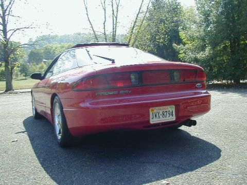 1997 Ford Probe - The rear of a red 1997 Ford Probe GT is visible, parked outdoors on a sunny day.