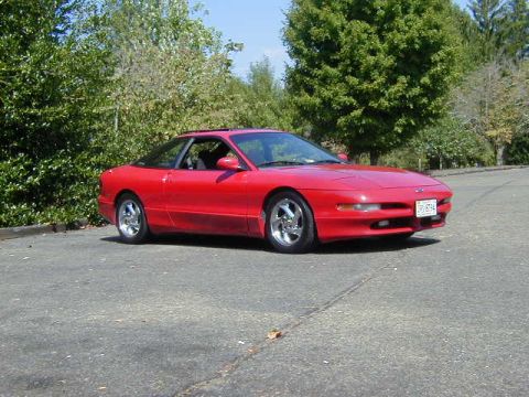1997 Ford Probe - Red 1997 Ford Probe GT coupe with chrome wheels sits on asphalt near trees.