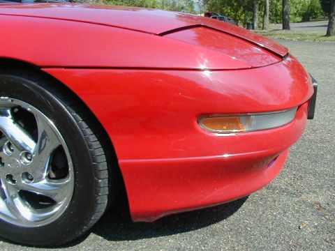 1997 Ford Probe - The front corner of a red 1997 Ford Probe is visible, showing the headlight and turn signal assembly.