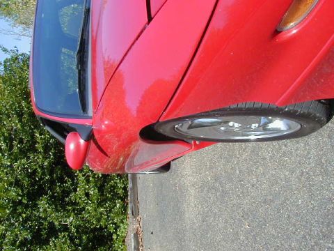 1997 Ford Probe - The front quarter panel and wheel of a red 1997 Ford Probe are visible.