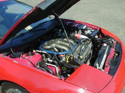 1997 Ford Probe - The engine compartment of a red car is visible with the hood raised, revealing the engine and other mechanical parts.
