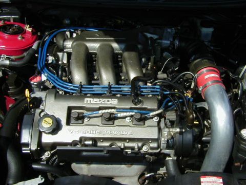 1997 Ford Probe - Engine bay view of a Mazda V6 DOHC 24-valve engine, a red intake hose and blue spark plug wires.