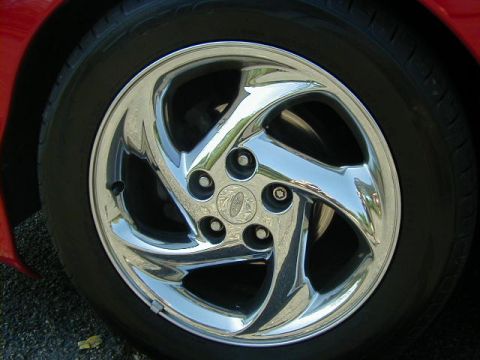 1997 Ford Probe - A close-up view of a shiny chrome wheel and tire on a red vehicle, a Ford emblem.