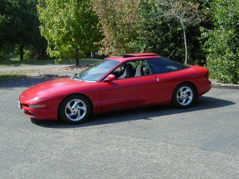 1997 Ford Probe - A red 1997 Ford Probe is parked outdoors on a paved surface with trees in the background.