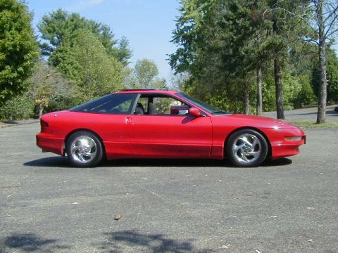 1997 Ford Probe - A red 1997 Ford Probe is shown from the side in a parking lot with trees and a clear sky.