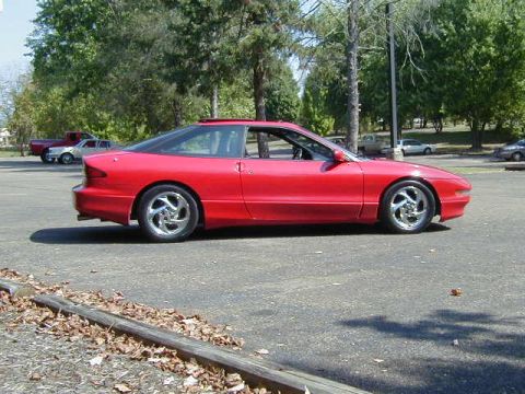 1997 Ford Probe - Side profile of a red 1997 Ford Probe GT with a sunroof and custom wheels.