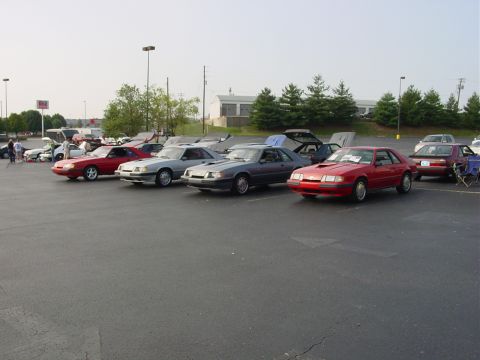 1986 Ford Mustang - A red 1986 Ford Mustang is parked in a lot alongside several other vehicles, possibly at a car show.