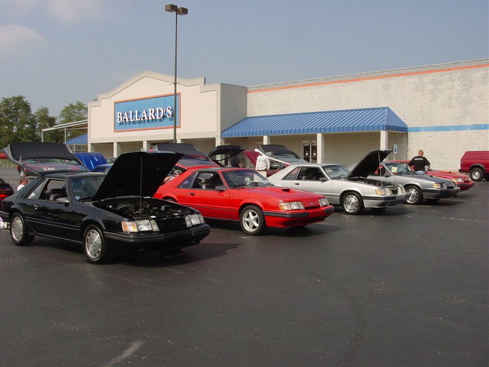 Black 1986 Ford Mustang coupe with hood open, parked in a lot with other cars