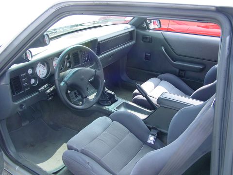 1986 Ford Mustang - The interior of a fox body Mustang features bucket seats and a manual transmission shifter.