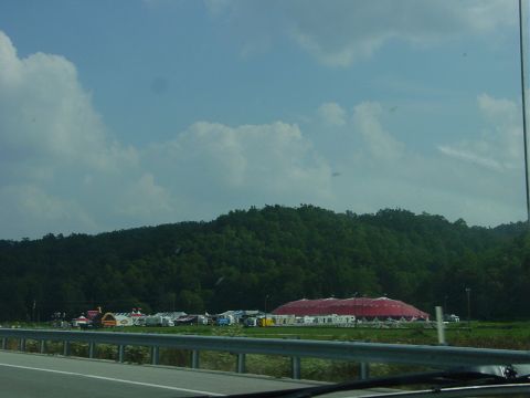 1986 Ford Mustang - A wide view of a landscape tents and a large red domed building, possibly a fairground or event site.