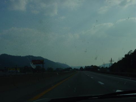 1986 Ford Mustang - View from inside a vehicle traveling on a highway, with mountains and a sign visible in the distance.