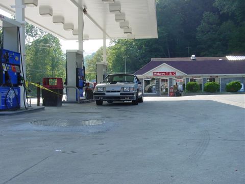1986 Ford Mustang - A silver 1986 Ford Mustang is parked at a gas station, with a convenience store in the background.