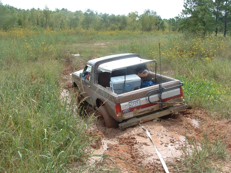 Brown 1993 Ford Bronco stuck in mud, rear view