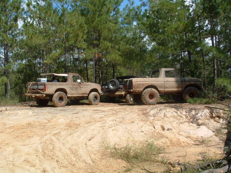 Muddy 1993 Ford Bronco and pickup truck on dirt road
