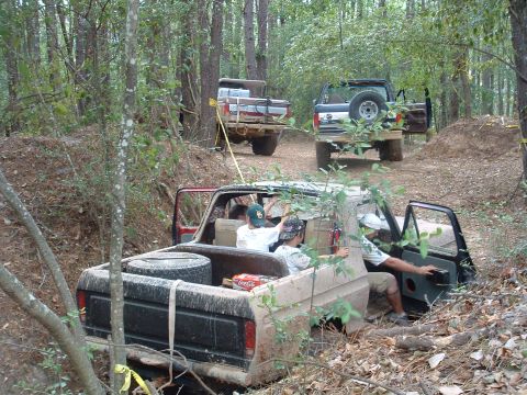 1993 Ford Bronco - Multiple Ford Broncos navigate a wooded trail during an off-road event.