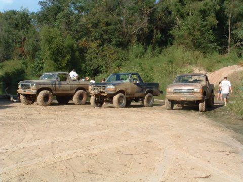 1993 Ford Bronco - Several off-road trucks are gathered on a dirt path, ready for adventure.