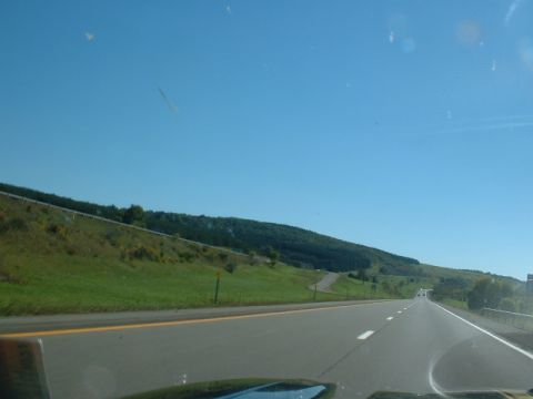 1978 Ford Mustang II - A view from a vehicle traveling on a highway through a rural landscape under a clear blue sky.
