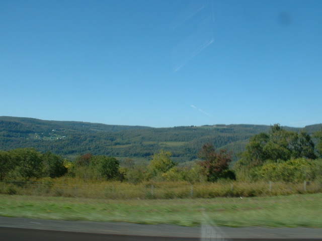 Scenic landscape with rolling hills and trees under a clear blue sky